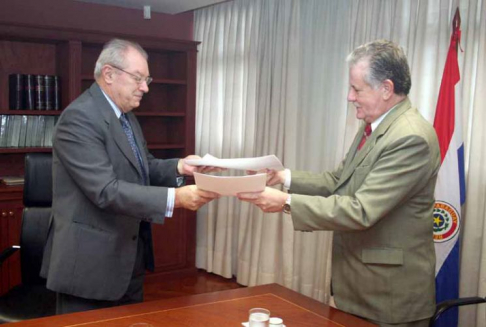Momento en que el presidente de la Corte Suprema de Justicia, doctor Víctor Núñez y el titular la La Ley Paraguaya se intercambian los documentos tras la firma del acuerdo.