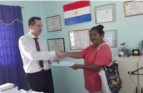 El magistrado Christian Bernal recibiendo el reconocimiento de la líder María Sasona.