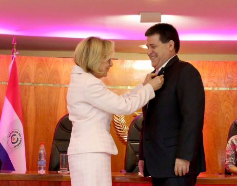 La presidenta de la Corte, Alicia Pucheta, colocando el lazo rosa de la lucha contra el cáncer de mama al presidente Cartes.